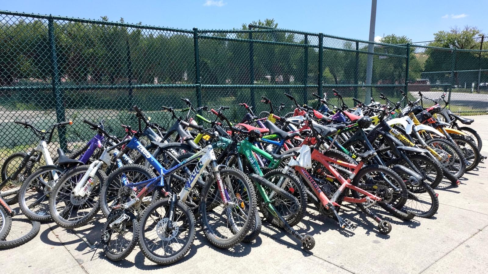 Disorganized pile of student e-bikes at a school fence